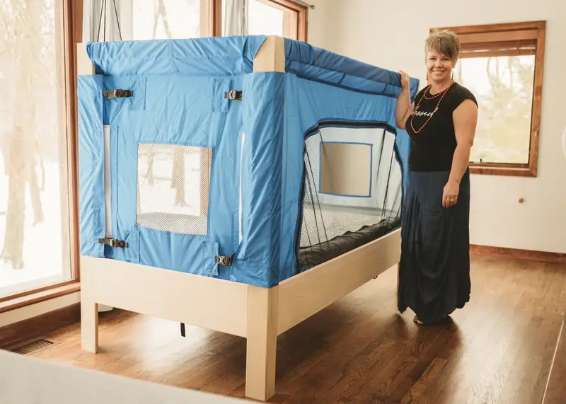 twin bed and bed tent with owner standing beside it